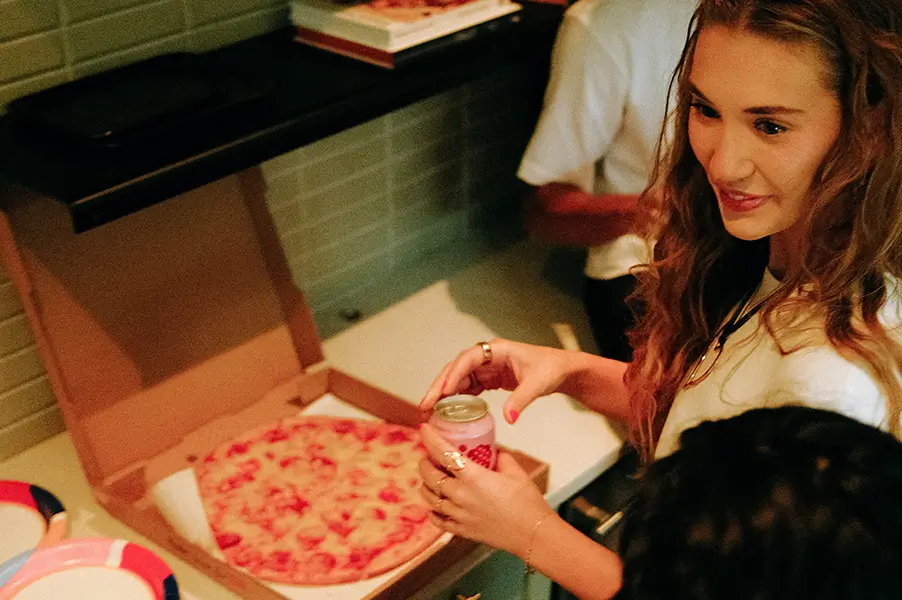 woman standing next to a pizza box